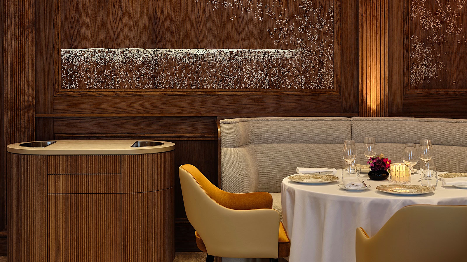 A table at Le Taillevent in Paris, backgrounded by wooden walls with a golden mural of bubbles.